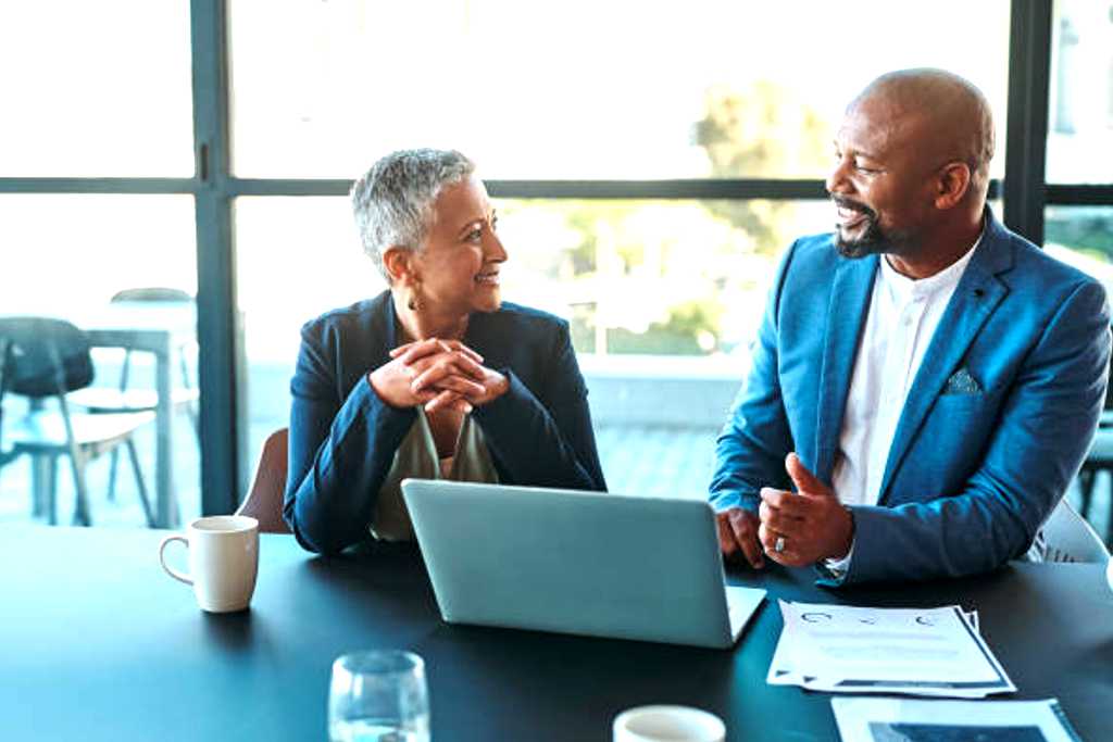 Engineers Meeting On Factory Floor Of Busy Engineering Workshop